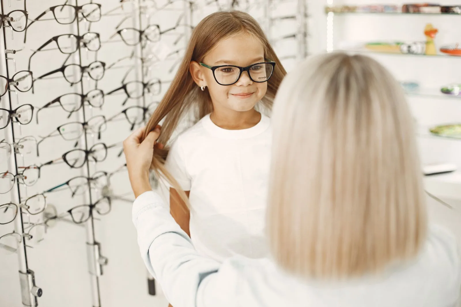 Jeune fille souriante essayant une paire de lunettes chez un opticien