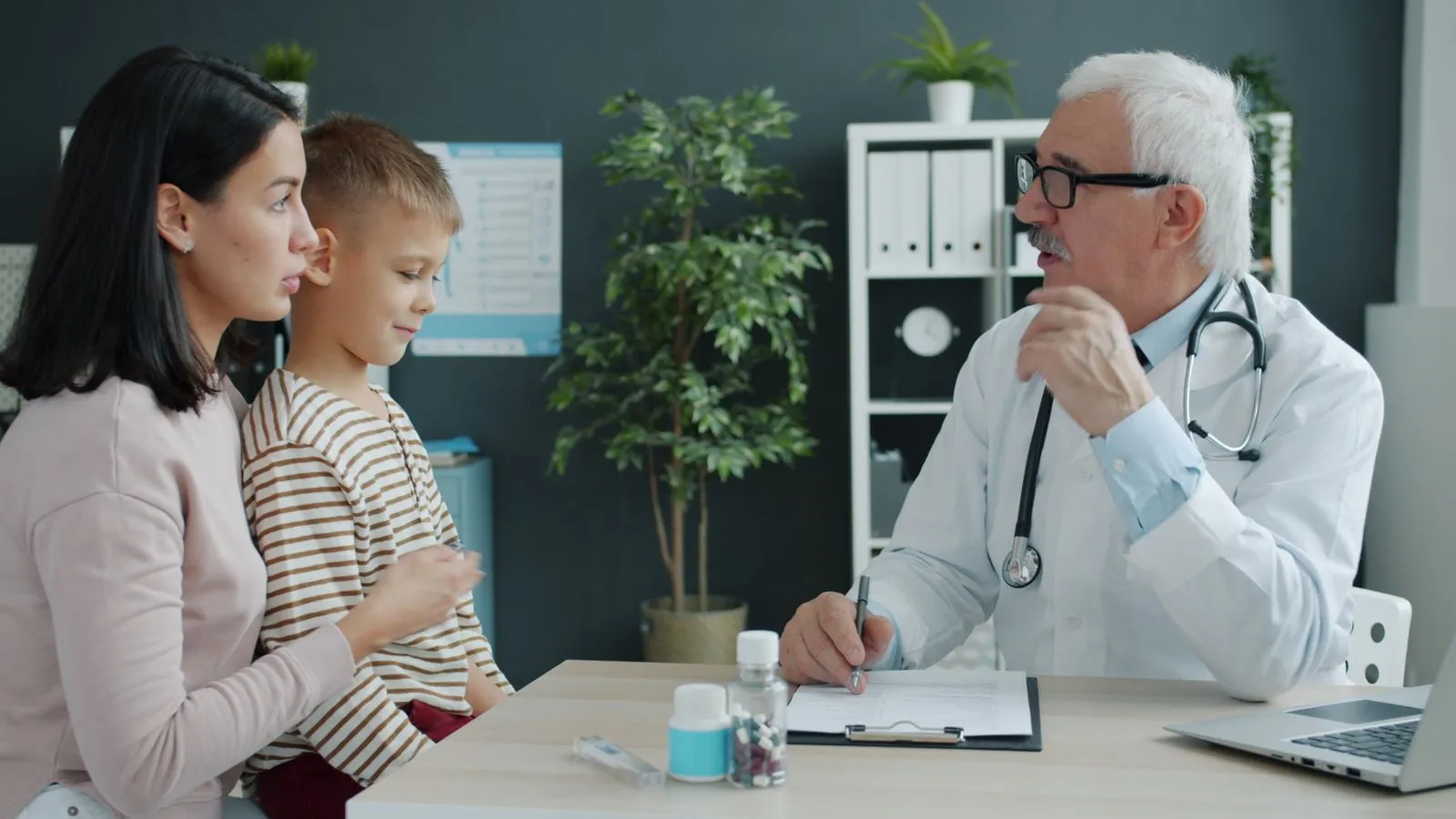 Médecin en consultation avec une mère et son enfant dans un cabinet médical
